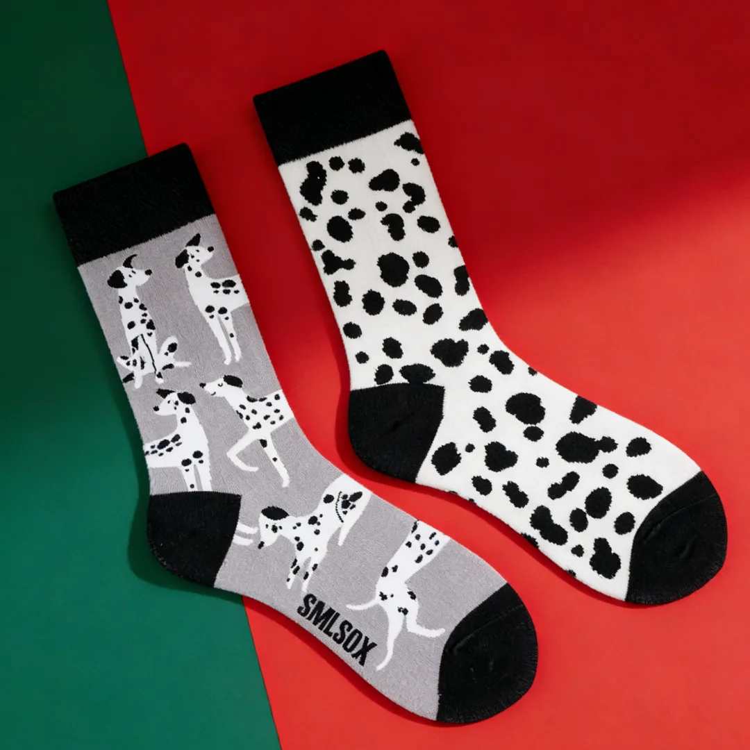 Two pairs of socks with dalmatian and cow print on a red and green background