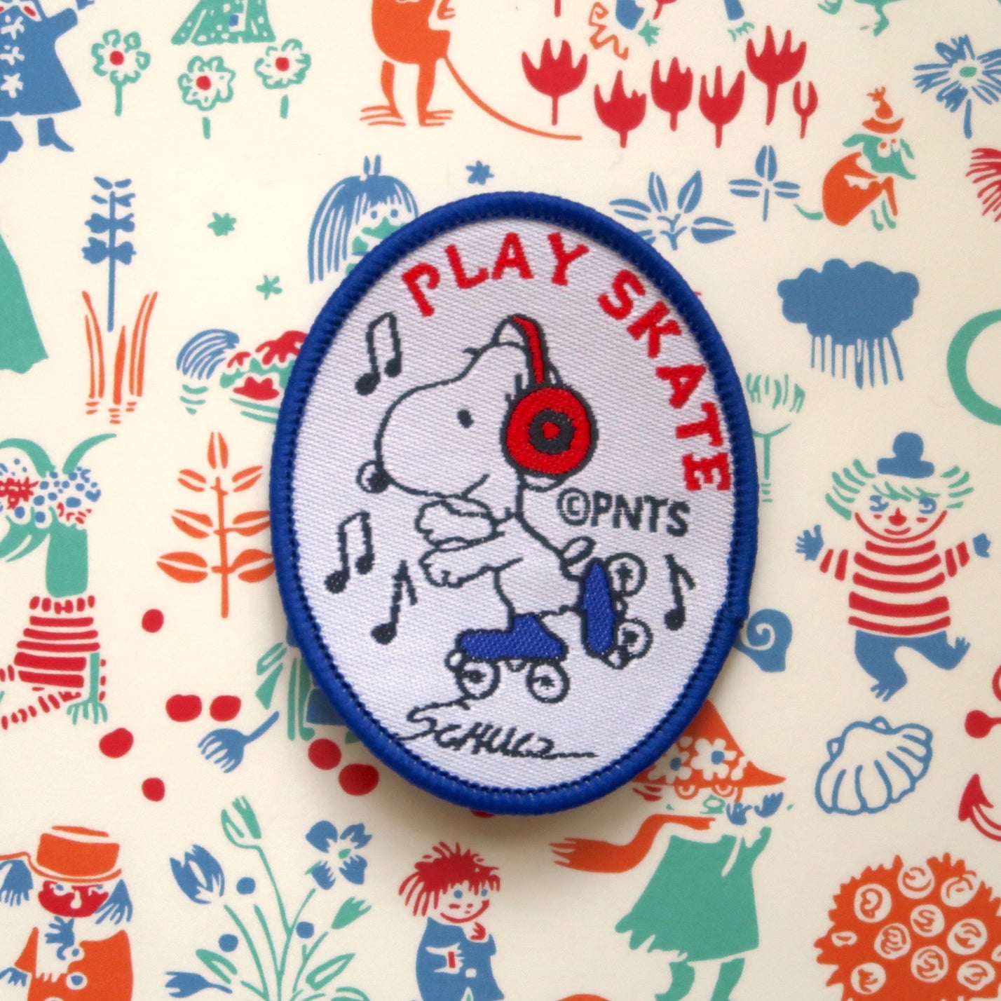 A white embroidered patch featuring Snoopy from the Peanuts comic strip with the text 'PLAY SKATE' and a blue border.