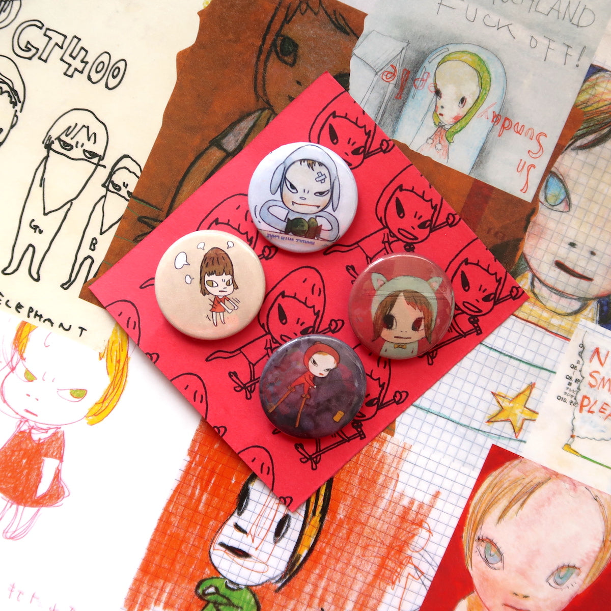 A set of vintage-style pin badges featuring anime-inspired characters, displayed on a surface with various artistic drawings.