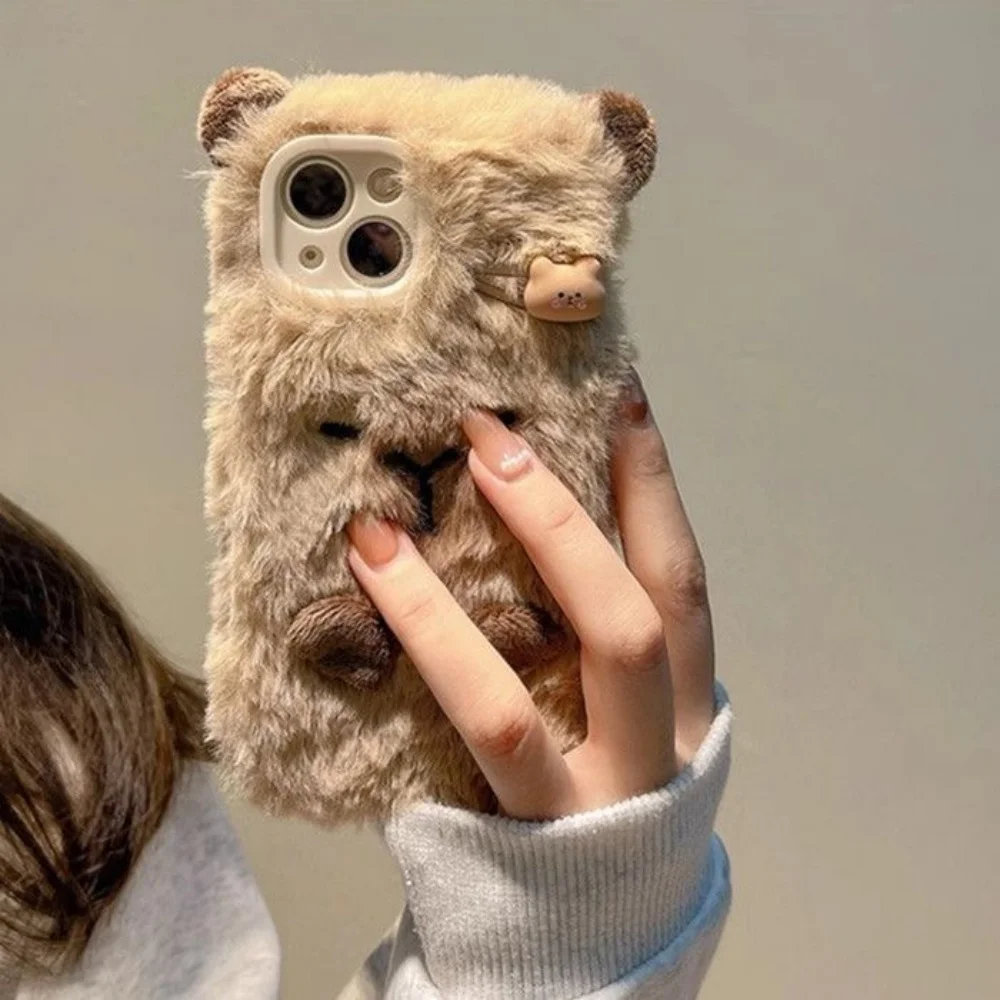 Person holding a phone with a fluffy bear phone case against a neutral background