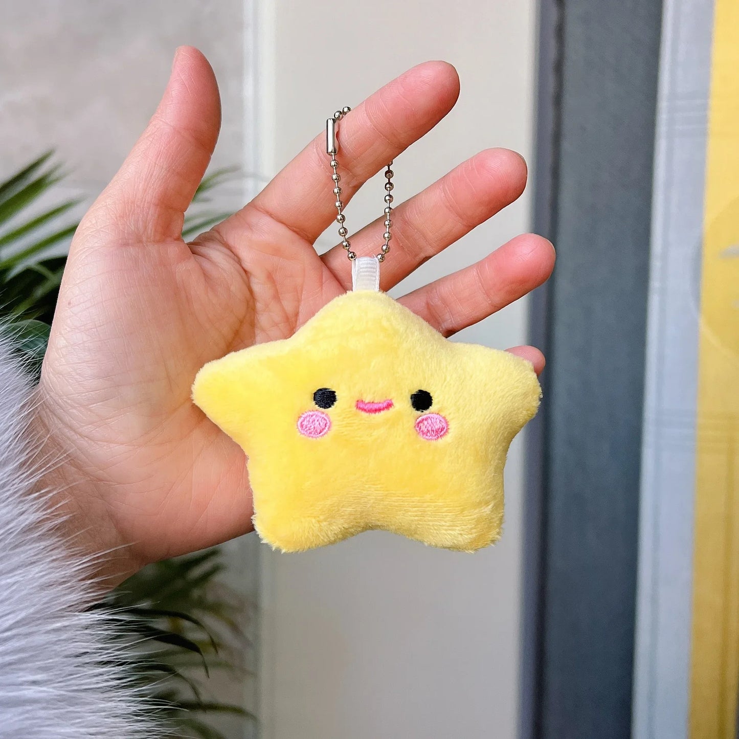Hand holding a yellow star-shaped plushie with a neutral background