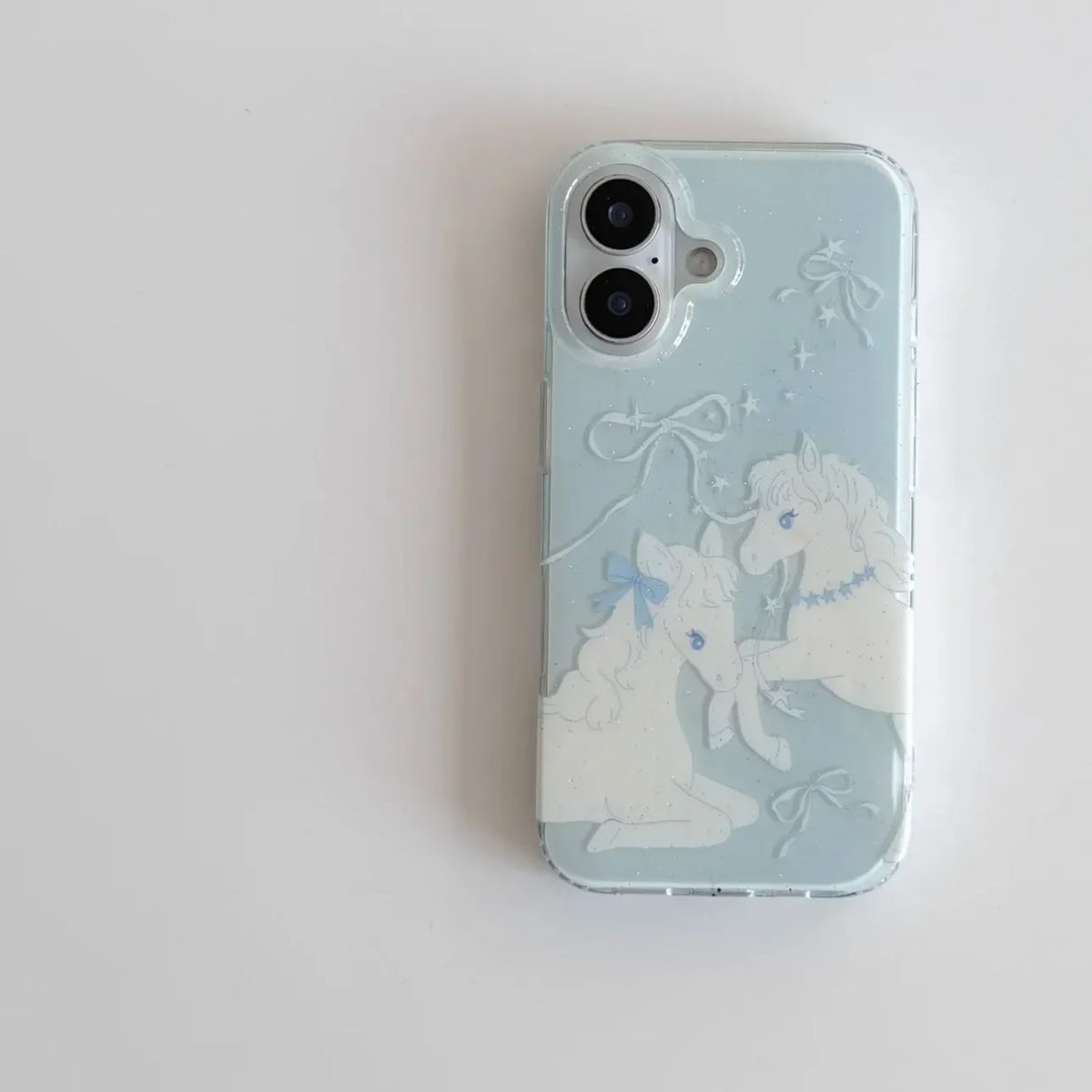 A light blue phone case featuring embossed white unicorns and bows, shown on a plain white background.
