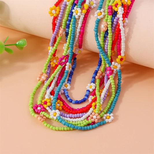 Colorful beaded flower necklaces on a beige surface