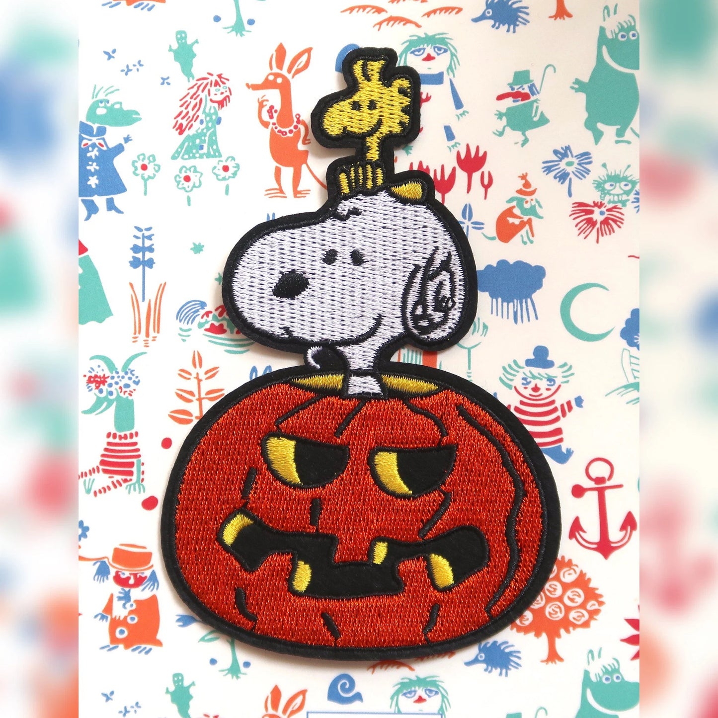 An embroidered iron-on patch featuring Snoopy and Woodstock from the Peanuts comics, with a pumpkin design.