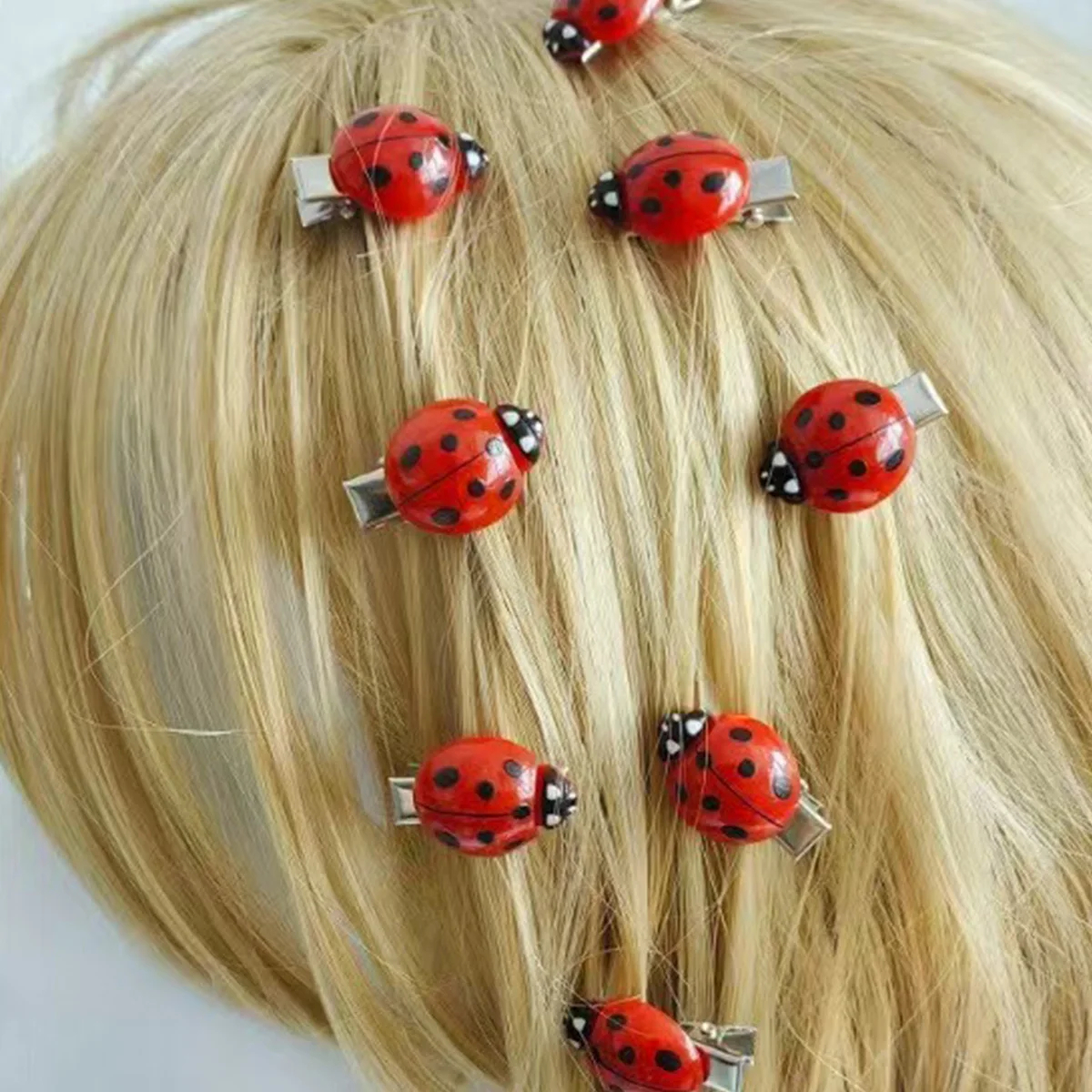 Blonde hair extensions with ladybug hair clips on a white background