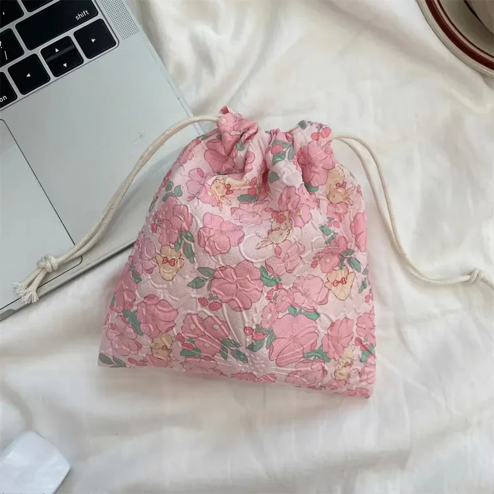 Floral drawstring bag on a white surface next to a laptop.