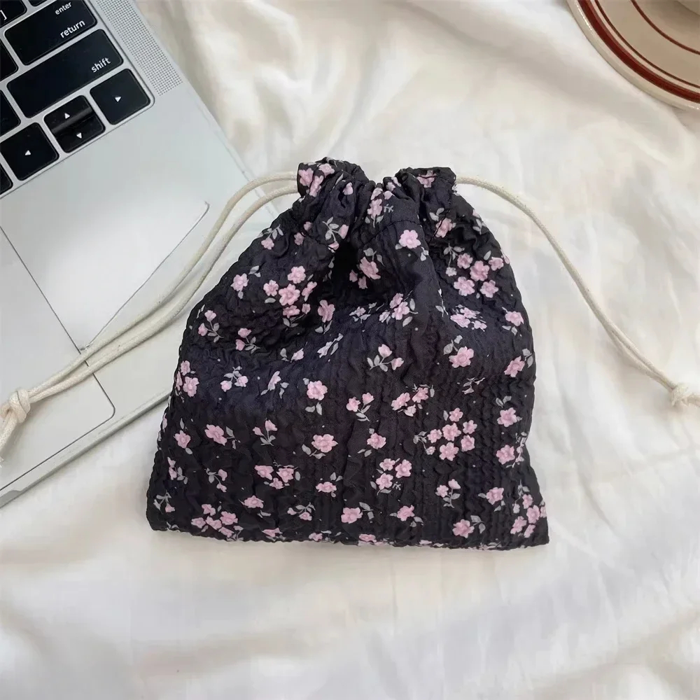 Floral drawstring bag on a light surface next to a laptop