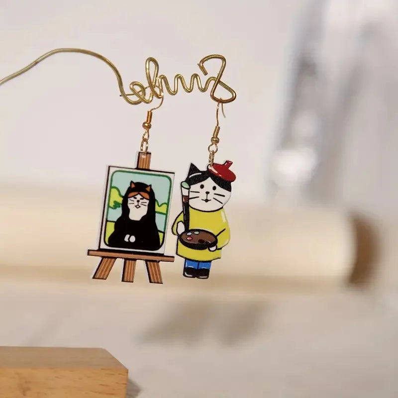 Pair of earrings with cartoon cat designs on a blurred background