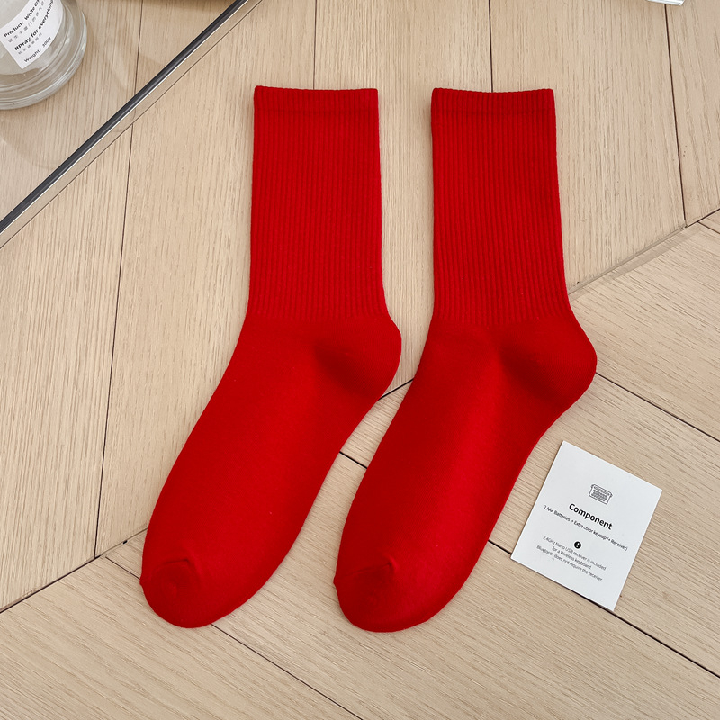 Pair of red socks on a wooden floor with a card beside them.