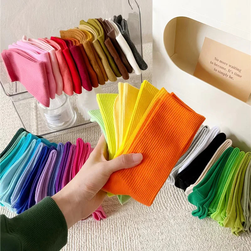 Colorful socks displayed in a store with a hand holding an orange sock.