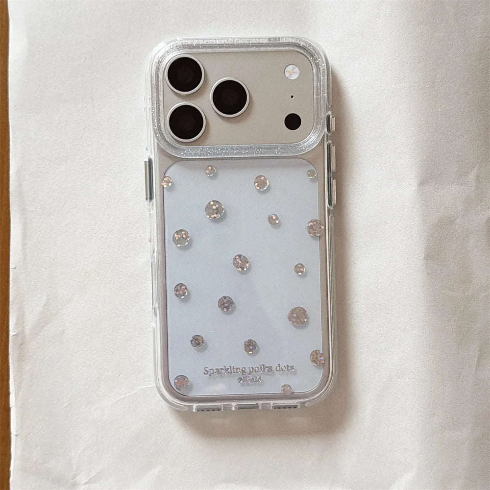 A clear protective phone case with a glittery silver border and scattered rhinestone embellishments, shown on a white phone against a textured off-white background.