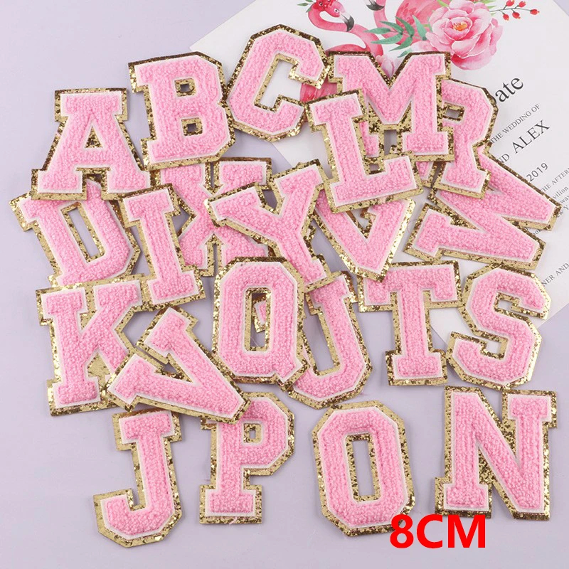 Pink letter patches with gold edges on a light purple background