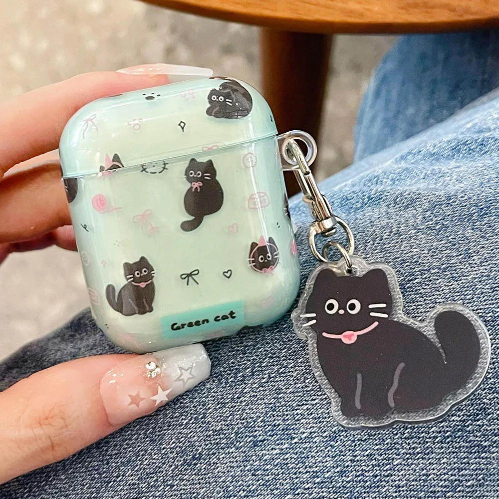 Mint green airpods case with black cat designs and a matching charm held by a hand.