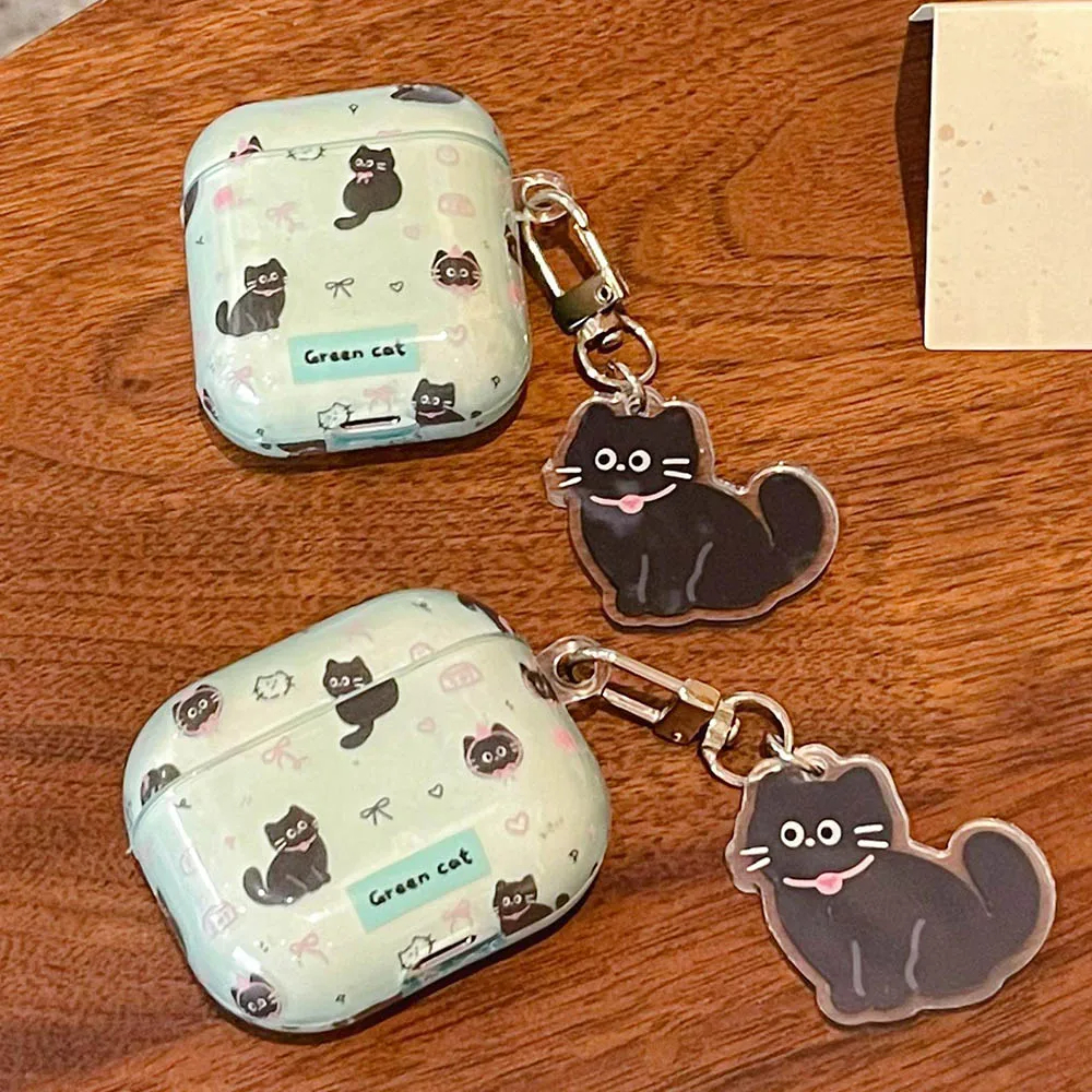 Two airpod cases with cat pattern and matching keychains on a wooden surface