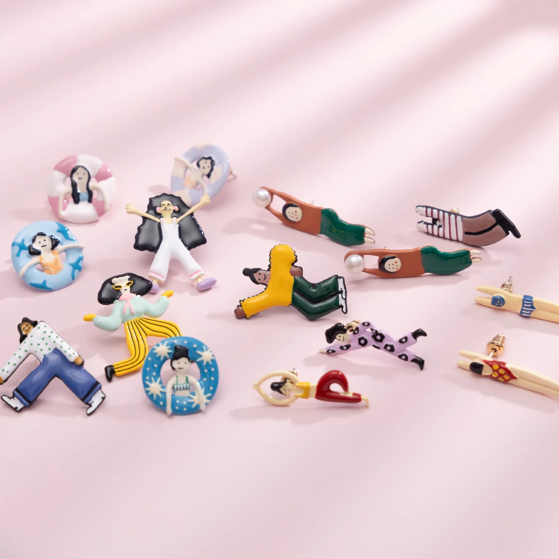 Colorful earrings with cartoon character designs on a pink background
