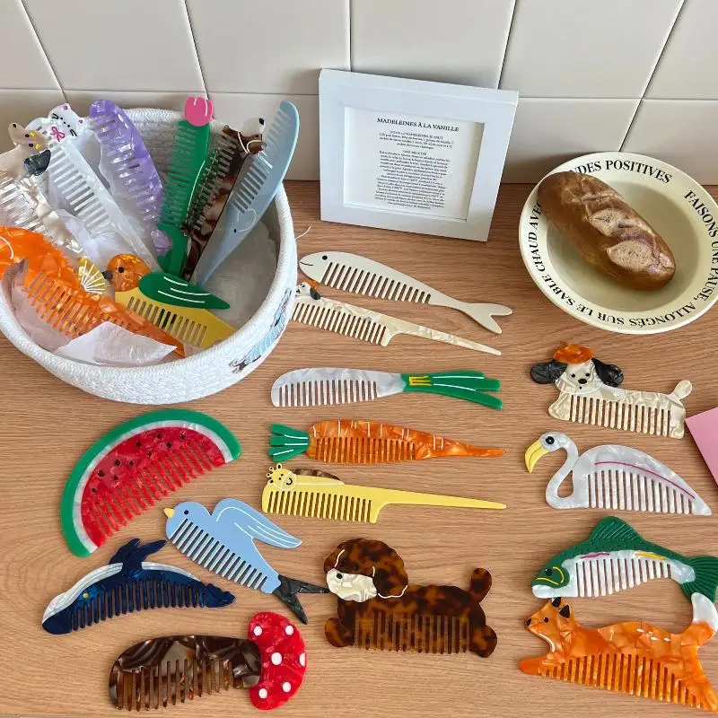 Collection of various animal-shaped combs on a wooden surface with a framed picture in the background.