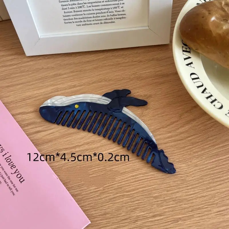 Whale-shaped comb on a wooden surface with text and a pink card.