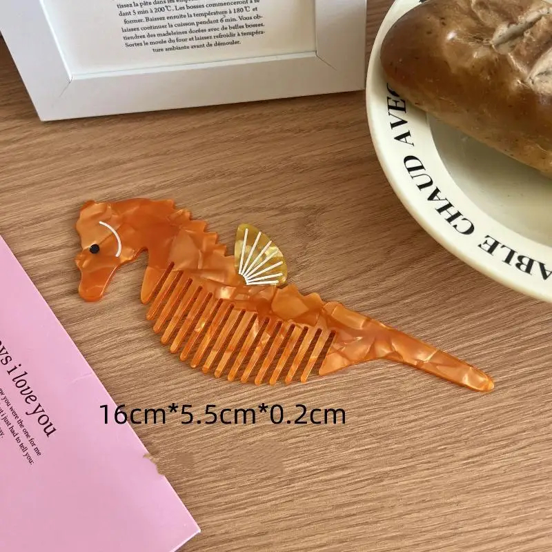 Orange seahorse-shaped comb on a wooden surface with text and a plate in the background.