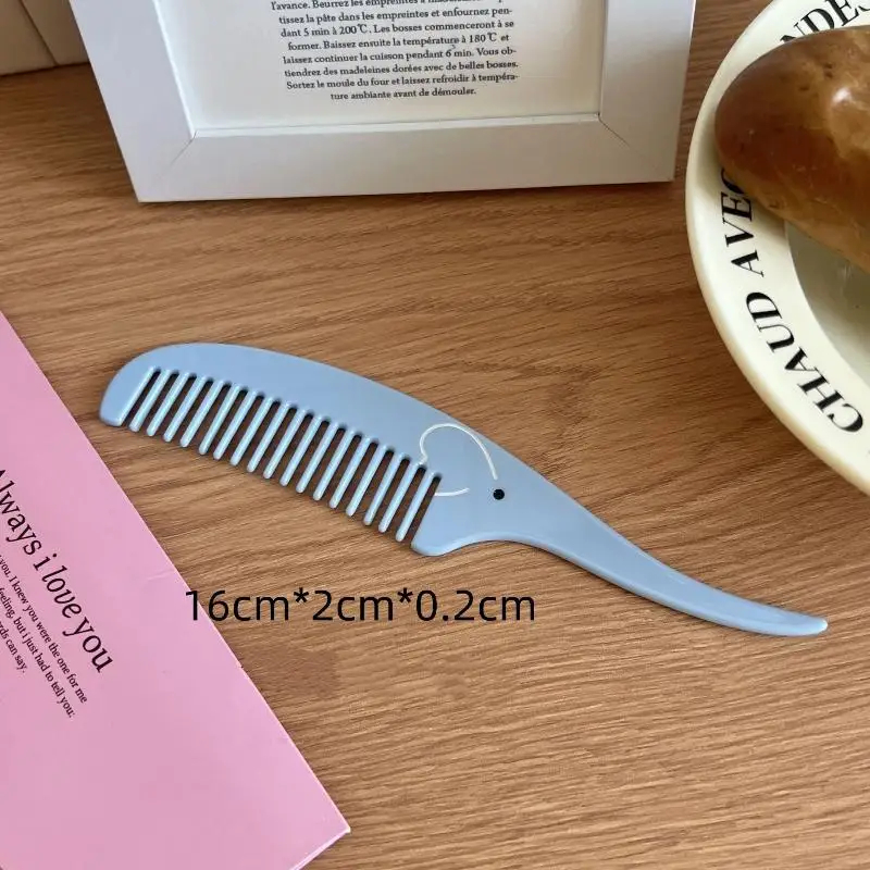 Blue comb with elephant design on a wooden surface next to a pink card and a white frame.