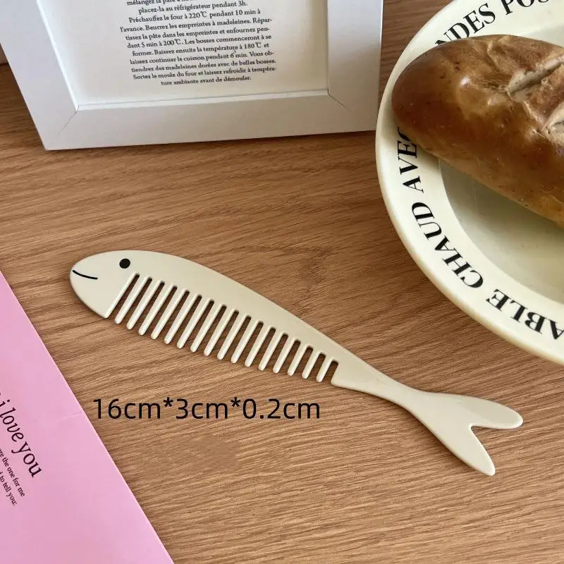 Fish-shaped wooden comb on a wooden surface with a plate of bread in the background.