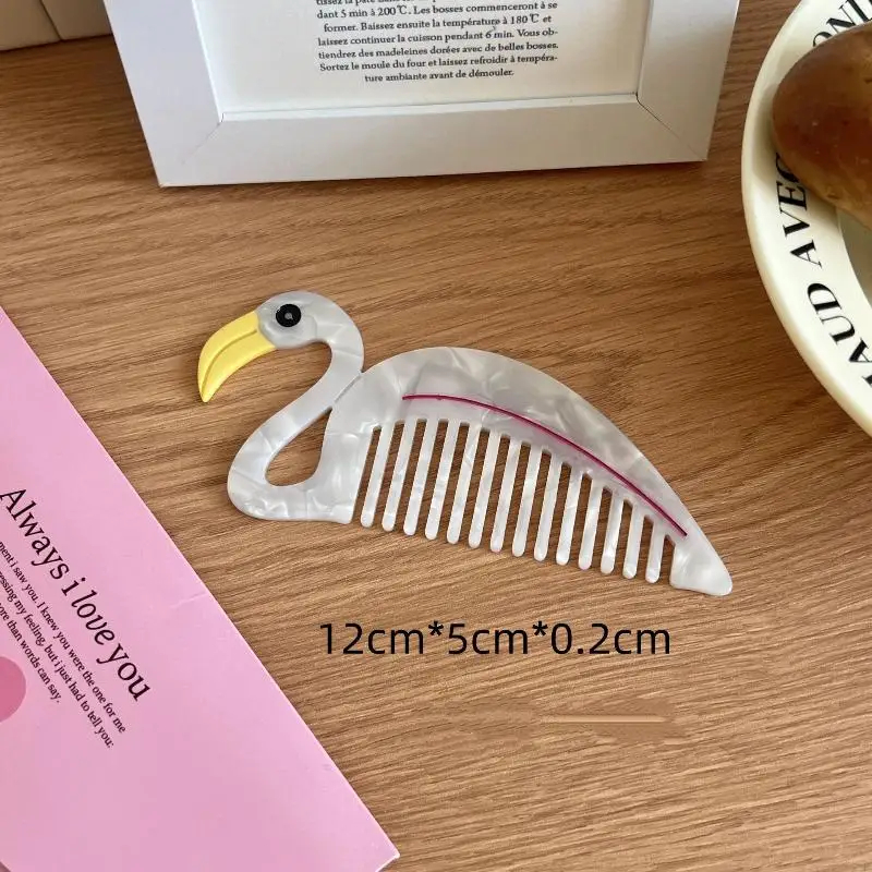 Flamingo-shaped comb on a wooden surface with dimensions displayed
