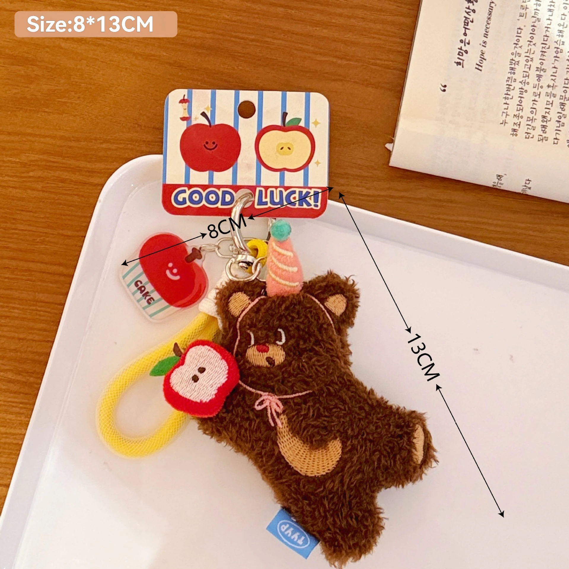Plush bear keychain with measurements on a white tray