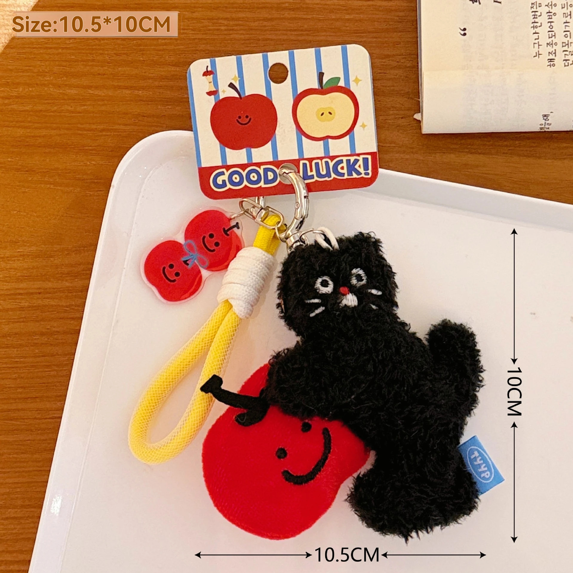 Black cat keychain with red apple on a white tray, with dimensions displayed.