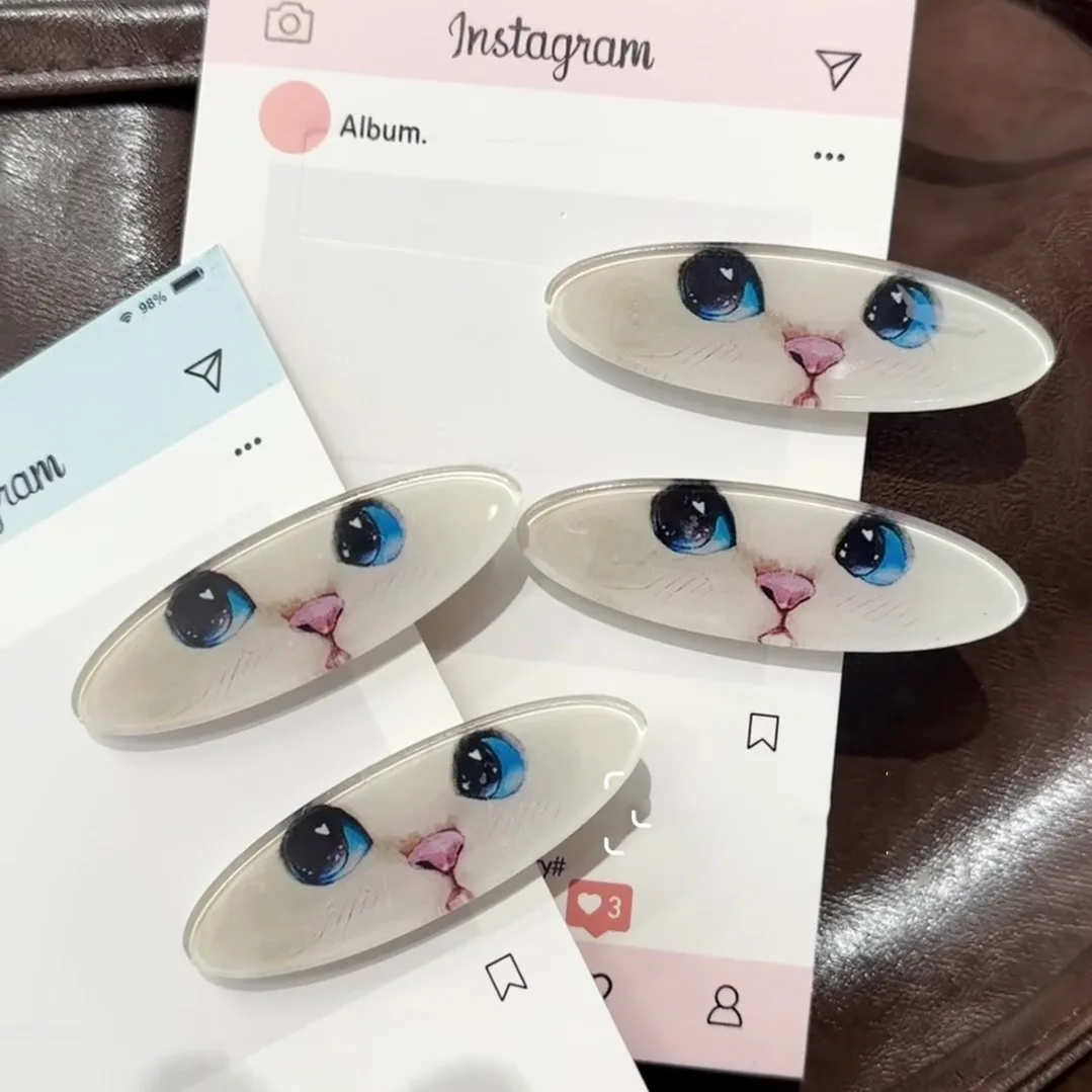 Cat-shaped hair clips with large eyes on a phone screen background