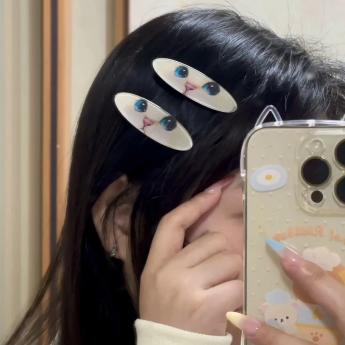 Person with cat-eye hair clips holding a phone with a cute case.
