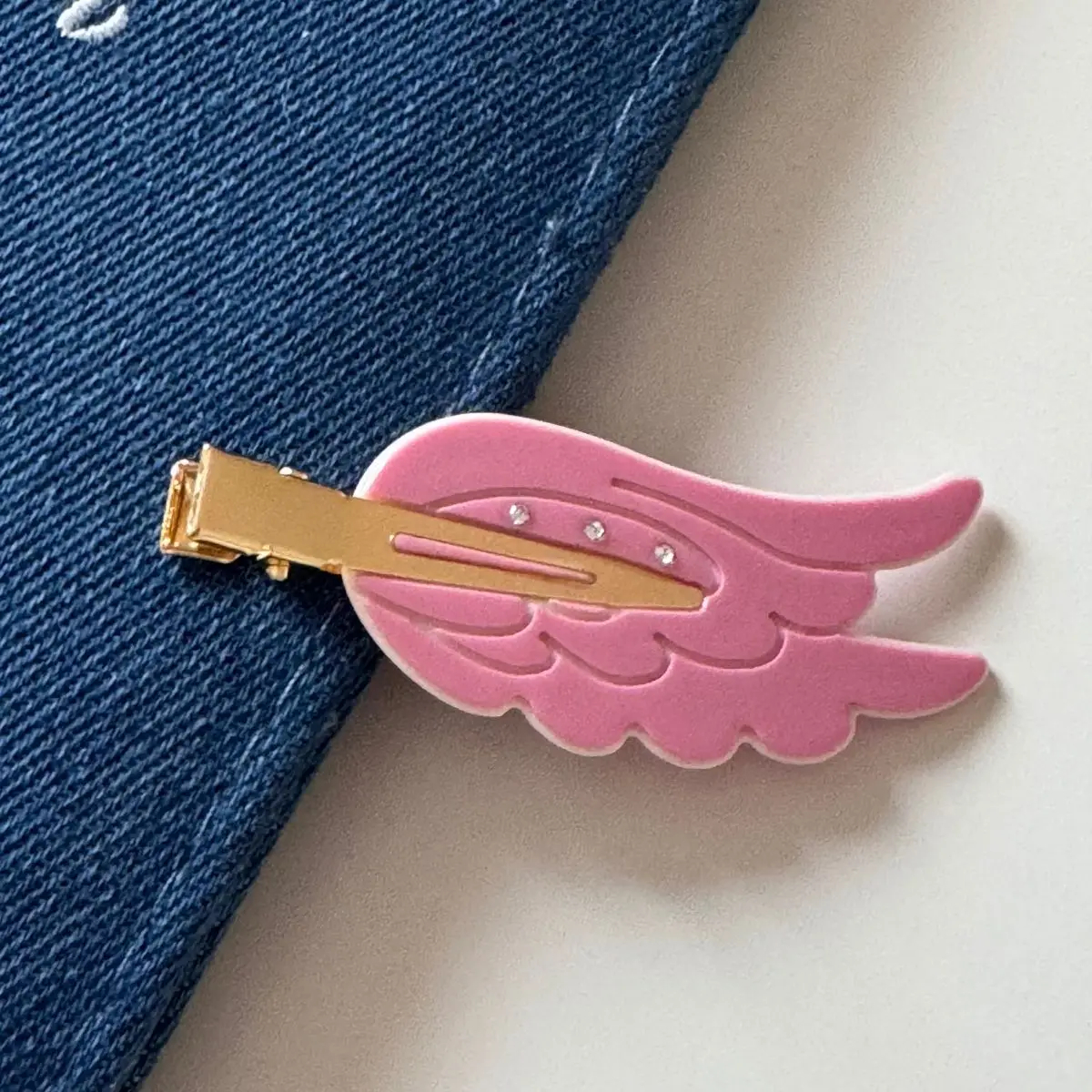 Pink hair clip with gold barrette on a denim background