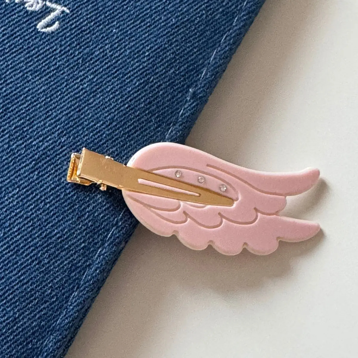 Pink wing-shaped hair clip on a denim background