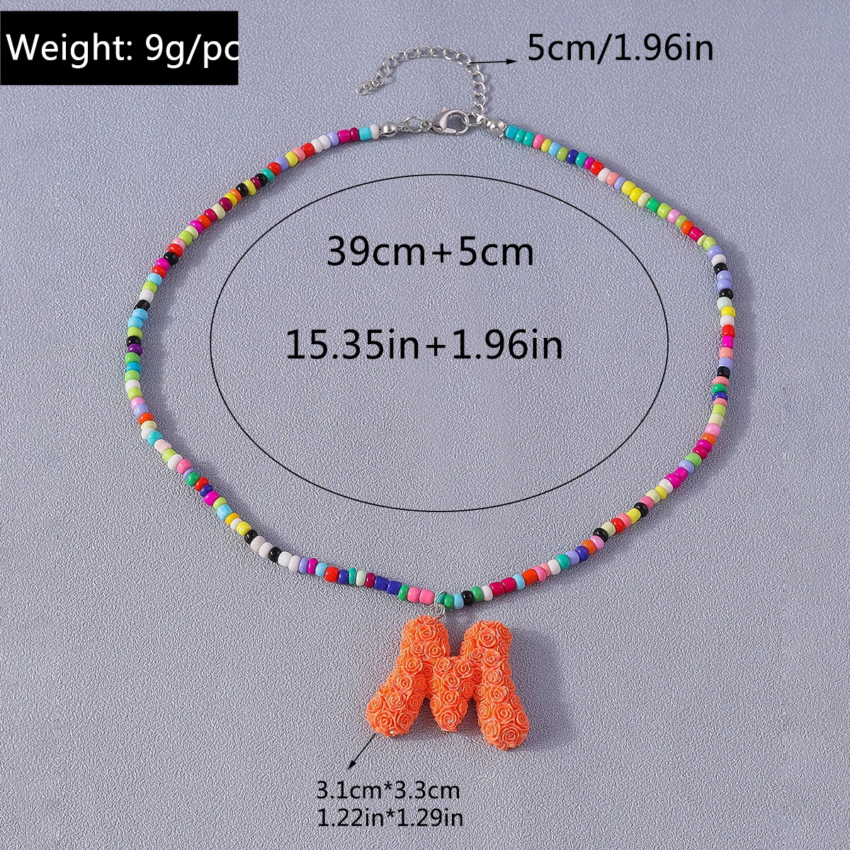 Colorful beaded necklace with an orange 'M' pendant on a gray background, showing measurements.