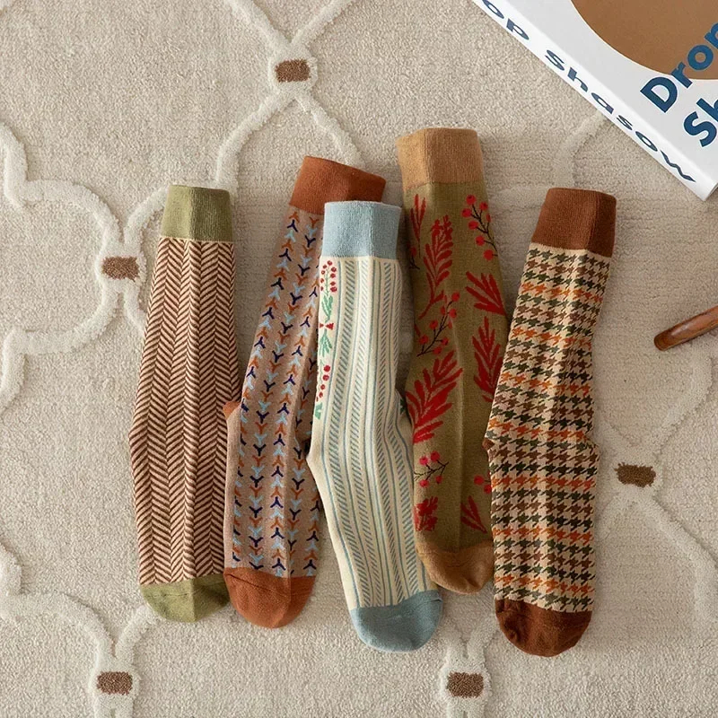 Five patterned socks on a textured surface with a magazine in the background.