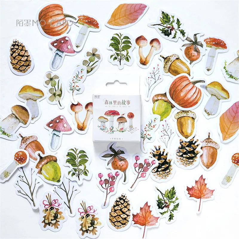 A set of autumn forest-themed sticker cutouts arranged around a small white product box on a white background. The stickers include mushrooms, acorns, pinecones, leaves, berries, and small botanical illustrations in warm fall colors.