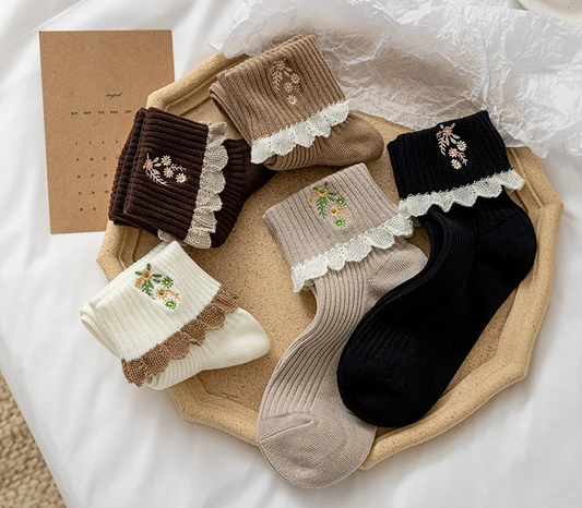 A collection of ruffled flower embroidery crew socks in various colors, displayed on a flat surface.