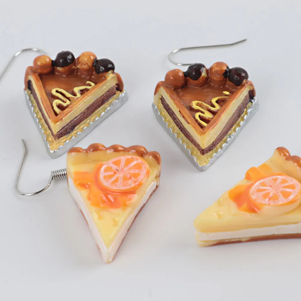 Two pairs of cake-shaped earrings on a white background