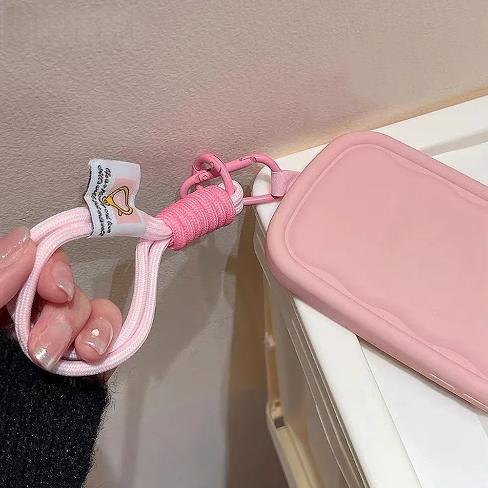 Pink lanyard with a small tag attached to a pink case on a beige background