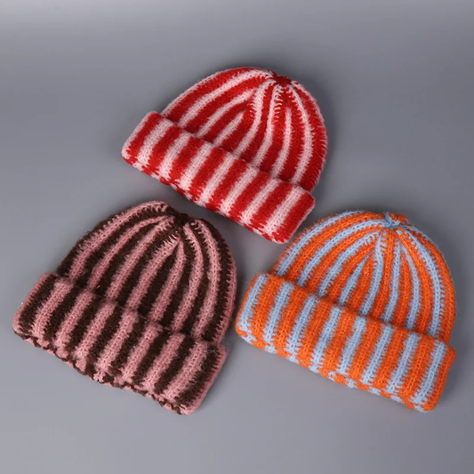 Three striped knit hats in red, brown, and orange on a gray background
