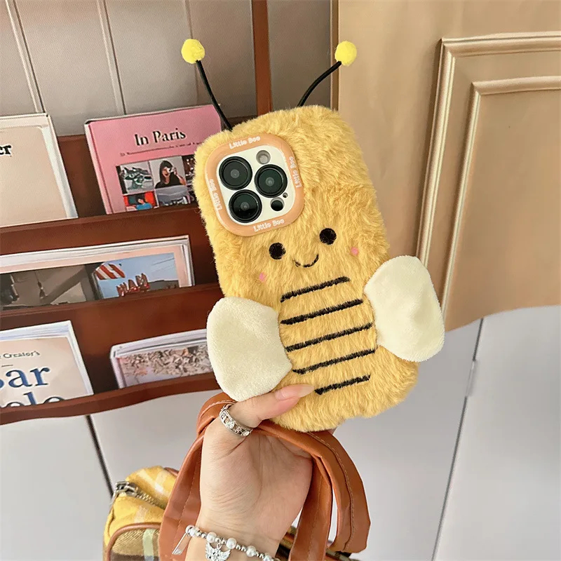 Hand holding a plush bee-shaped phone case with a decorative background