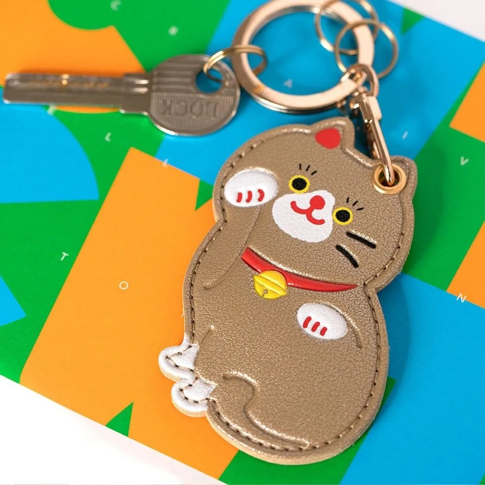 Cat-shaped keychain on a colorful geometric background