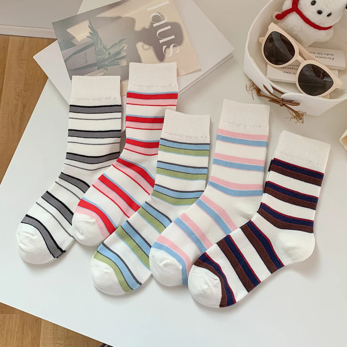 Set of striped socks on a white surface with sunglasses and a snowman decoration in the background.