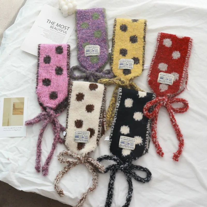 Colorful knitted headbands with polka dot patterns on a white surface.