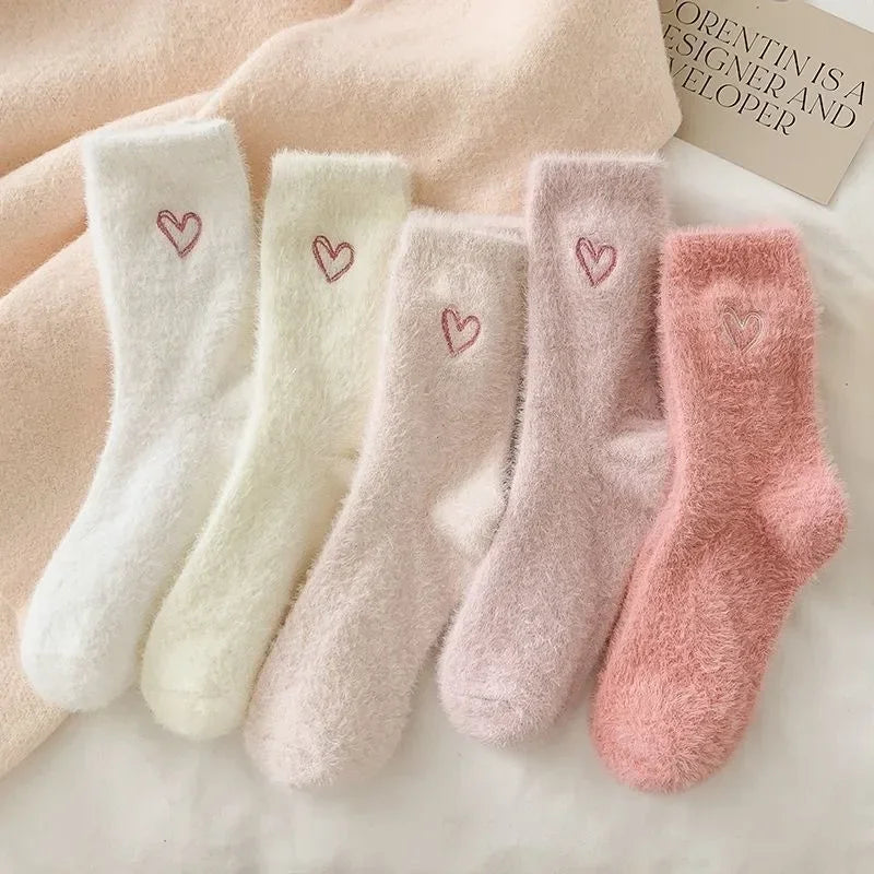 Set of four soft socks with heart designs in various colors on a light background.