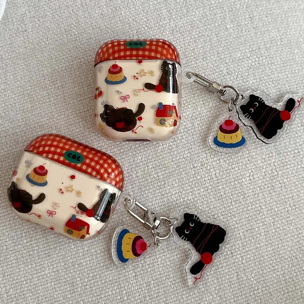 Two small rectangular cases with cat-themed designs and matching keychains on a textured surface.