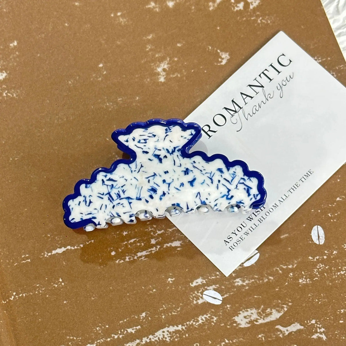 Decorative blue and white object on a brown surface with a card reading 'ROMANTIC Thank you'.