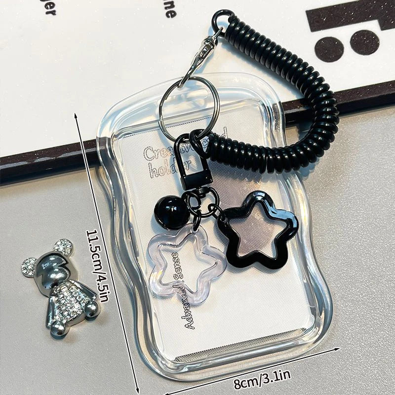 Clear keychain holder with black star-shaped charm and coiled black cord on a light gray background.