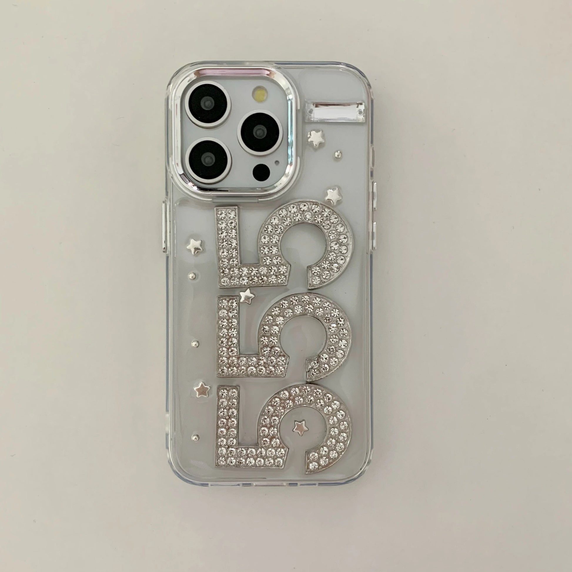 A clear phone case with '555' spelled out in large, rhinestone-covered letters, embellished with small star accents, shown on a light gray background.