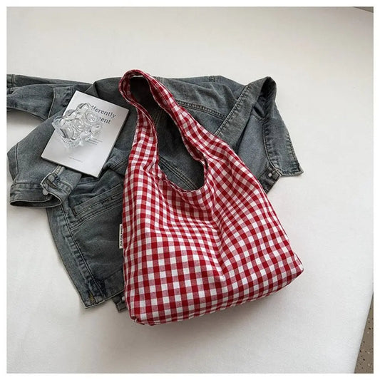 Red and white checkered bag with denim jacket and book on light background