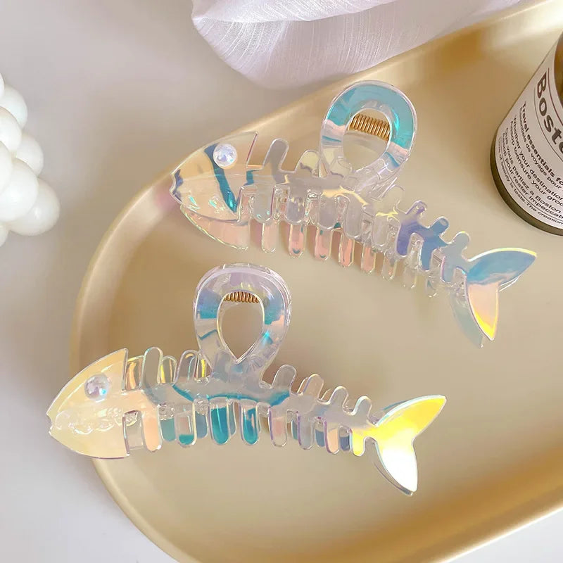 Iridescent fish-shaped hair clips on a gold tray with a blurred background