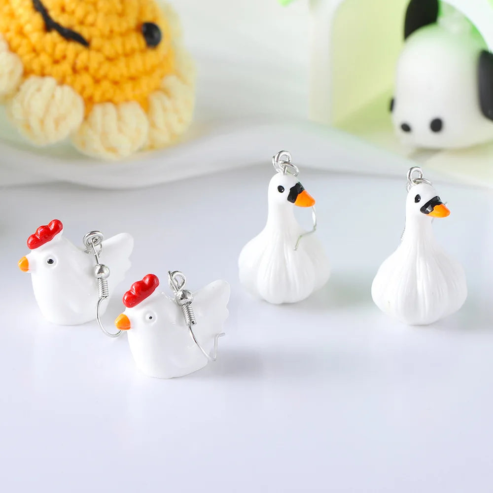 Small white chicken-shaped charms with red combs on a light background